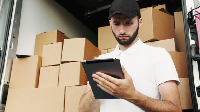 A man looking at his tablet, thinking about how to choose the best shipping carrier.Â
