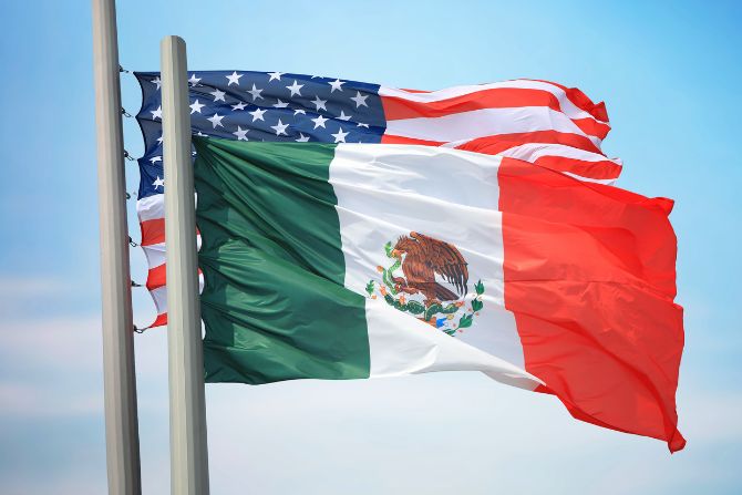 Flags of Mexico and the United States waving together, symbolizing the trade relationship and the impact of the 2025 tariffs.